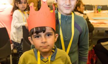 two boys standing, wearing crowns they have made